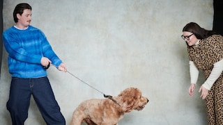 Man Holds Dog as Woman Coaxes