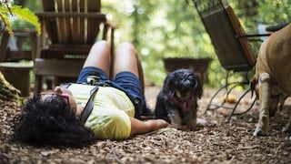 Woman lies on the floor with bent legs while the dog stands beside her
