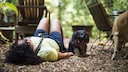 Woman lies on the floor with bent legs while the dog stands beside her