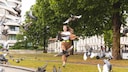 A woman approaches pigeons, causing them to fly away.