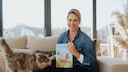Judith Rakers sits on a couch with a cat, presenting her children's book.