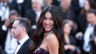 Rebecca Mir in a black latex dress on the red carpet in Cannes. She laughs radiantly into the camera