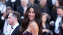 Rebecca Mir in a black latex dress on the red carpet in Cannes. She laughs radiantly into the camera