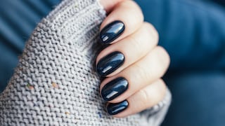 Woman's hand with dark blue nail polish and gray knitted sweater