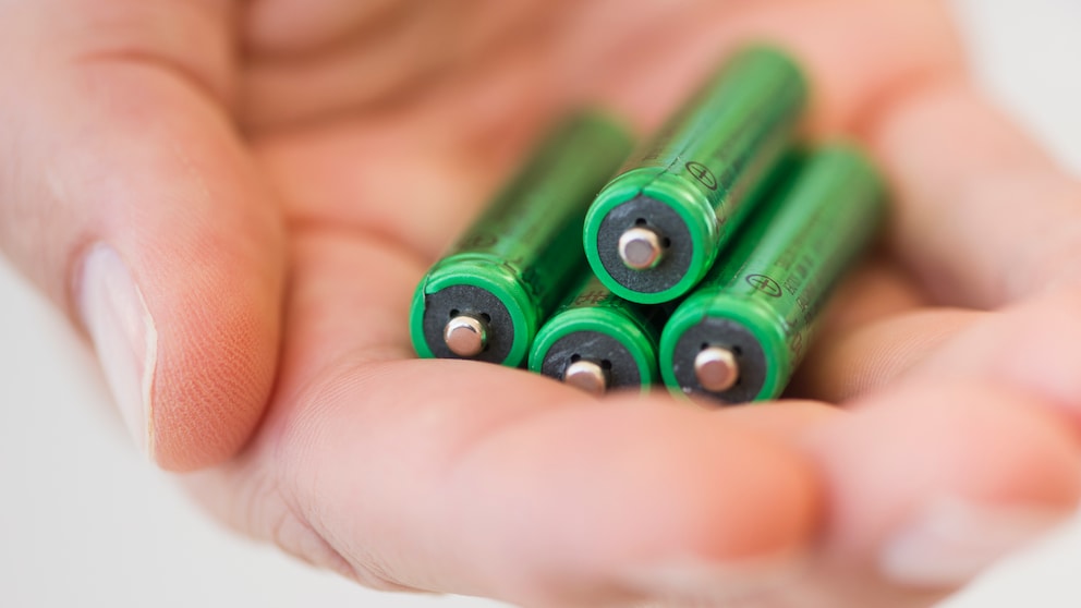 Hand with four AAA batteries