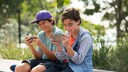 Mobile Games: Two Boys Sit Side by Side with Their Smartphones