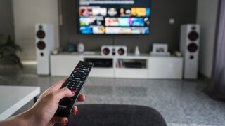 Woman Sits with Remote Control in Front of TV