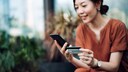 Woman Makes International Transfer via App Using Smartphone and Credit Card