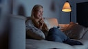 Smiling Woman on the Sofa Watches the Best TV Shows