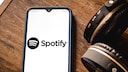 Spotify App to Get Home Feed and Smart Shuffle: Spotify Logo on Smartphone Next to Headphones