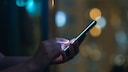 WhatsApp Notification Symbol: Phone in Hand Against Dark Background
