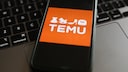 Temu Online Shop: Logo on Smartphone Resting on Keyboard
