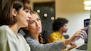 Stock Image Interview Güncem Campagna tech and teach: Two Women with Laptop Talking to Each Other