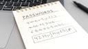 Illustrative image: A note with several crossed-out passwords in front of a laptop.