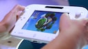 Two hands hold a white Wii U and play a game.