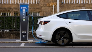 Stock Image: White electric car charging at a charging station.