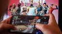 A person plays "Fortnite" on their phone, with a game-themed wallpaper visible in the background.
