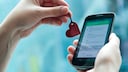 Stock photo: A hand holds a heart-shaped NFC tag in front of a smartphone