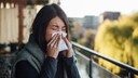 Stock Image: A woman blows her nose due to a grass allergy