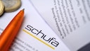Schufa documents next to a pen and coins.