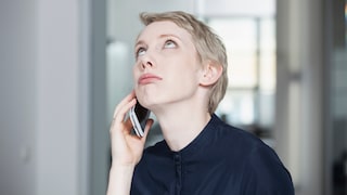 Woman holds a smartphone to her ear and looks up.