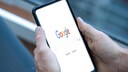A person holds a smartphone with an open Google search.