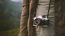 Someone has a compact camera on a strap around their neck