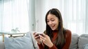 A woman plays a game on her phone and is delighted.