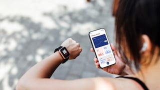Woman holds a smartwatch and a smartphone in her hand