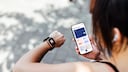 Woman holds a smartwatch and a smartphone in her hand