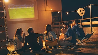 Stock photo: A group of friends watching soccer projected onto a screen.
