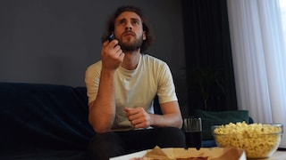 Man Sits with Skeptical Look in Front of TV