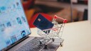 Credit card in a mini shopping cart on a laptop.