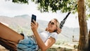 Stock photo: Woman enjoying her vacation in a hammock with a smartphone.