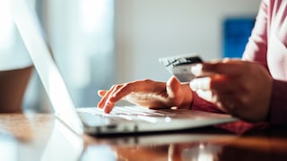 Person sitting at laptop with credit card in hand