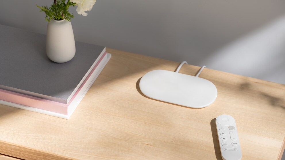 White Google TV streamer with remote control on cabinet