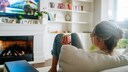 Woman sits on the sofa with popcorn and watches TV