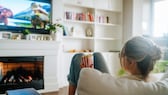 Woman sits on the sofa with popcorn and watches TV