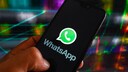 Person holds a smartphone displaying WhatsApp in their hand