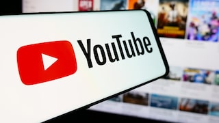 YouTube logo on a smartphone with video thumbnails in the background