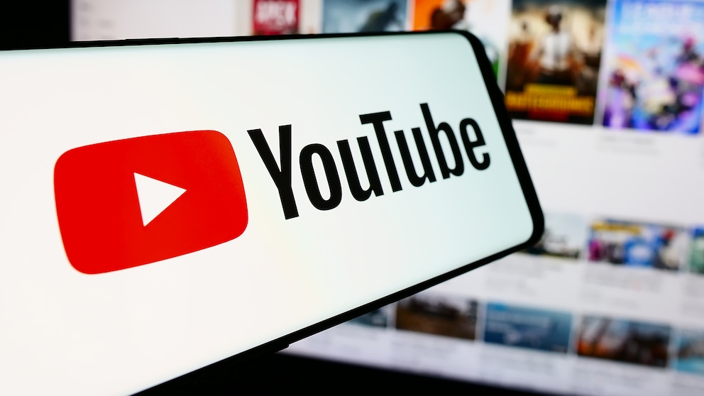 YouTube logo on a smartphone with video thumbnails in the background