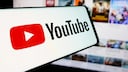 YouTube logo on a smartphone with video thumbnails in the background