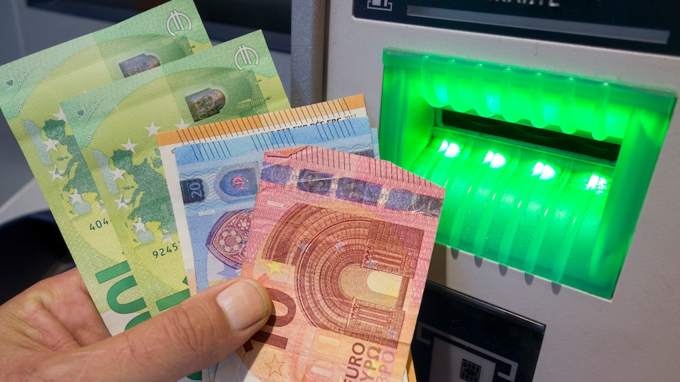 Person holds cash in hand at an ATM