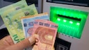 Person holds cash in hand at an ATM
