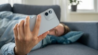 Person is lying on the sofa and looking at their smartphone