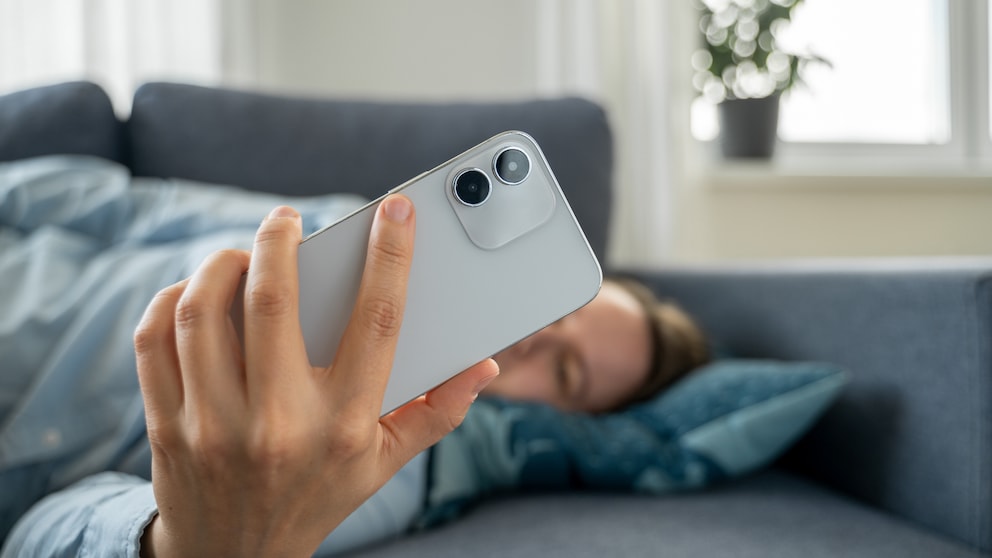 Person is lying on the sofa and looking at their smartphone