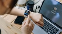 Smartwatch on wrist with laptop in the background