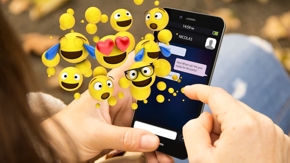 Person looks at a smartphone with lots of emojis floating above it