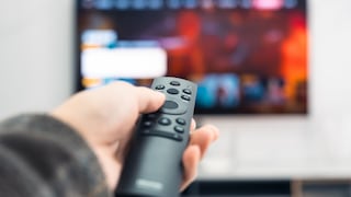 Person holds remote control pointed at TV