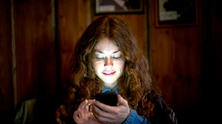 Woman looks at her smartphone in the dark